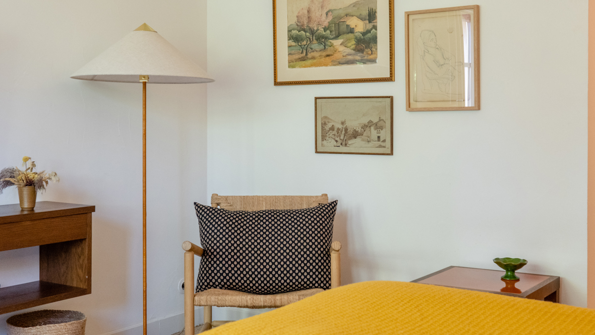 Une chaise confortable est placée dans le coin avec une lampe sur pied et des portraits au-dessus.