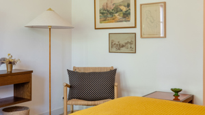 Une chaise confortable est placée dans le coin avec une lampe sur pied et des portraits au-dessus.