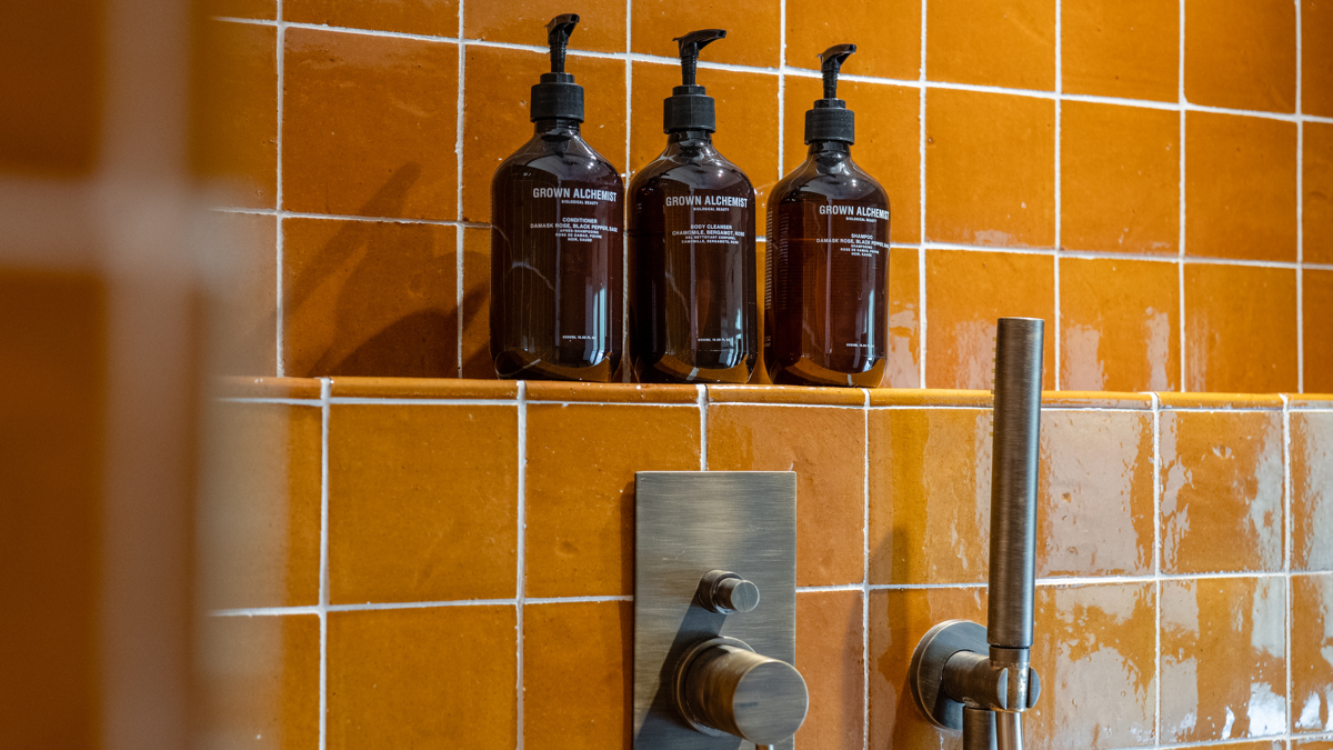 Trois bouteilles de bain sont correctement disposées sur le support dans la salle de bain.