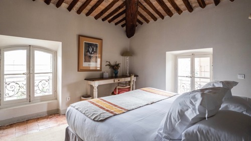 Une chambre bien rangée comprend un lit confortable, une table devant et un portrait au-dessus.