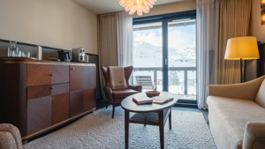 Espace de vie avec canapés confortables et placard près d’une fenêtre montagneuse enneigée.