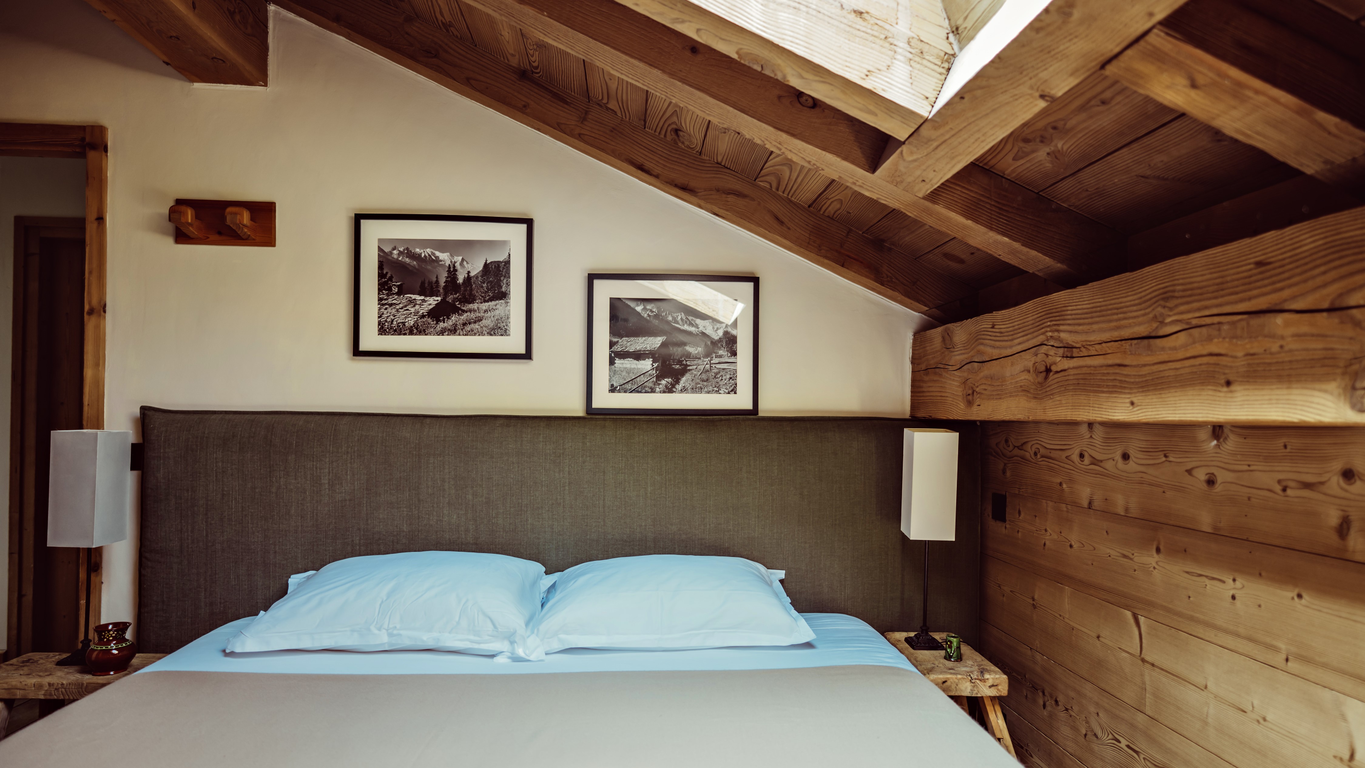 Cozy attic bedroom with sloped ceiling, gray headboard, and framed wall art