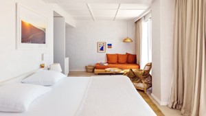 A well-organized bedroom features a cozy bed, a sofa set, and portraits on walls.