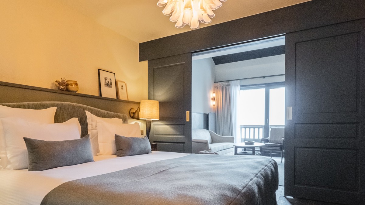 Une chambre bien organisée comprend un lit confortable avec un lustre suspendu au-dessus.