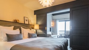 Une chambre bien organisée comprend un lit confortable avec un lustre suspendu au-dessus.