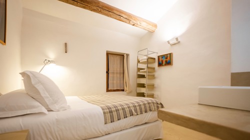 A tidy bedroom features a cozy bed, a corner frame, and front wall portrait.