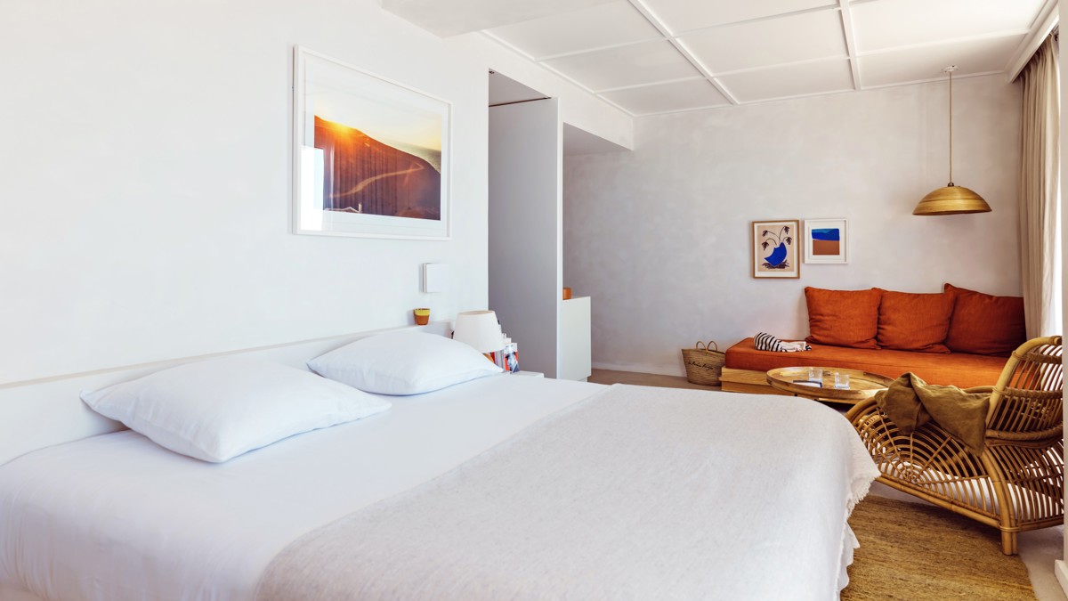 A well-organized bedroom features a cozy bed, a side table with a lamp, and portraits mounted overhead.