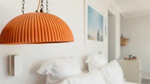 A photo captures a hanging lamp positioned beside the cozy bed.