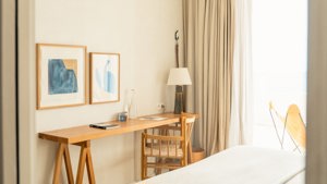 A chair is placed near the table, with two portraits mounted just above it.