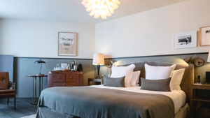 Une chambre bien organisée comprend un lit confortable, avec un élégant lustre suspendu au-dessus.