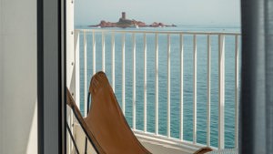 A relaxing chair is placed on the balcony, offering a wonderful view of the ocean.