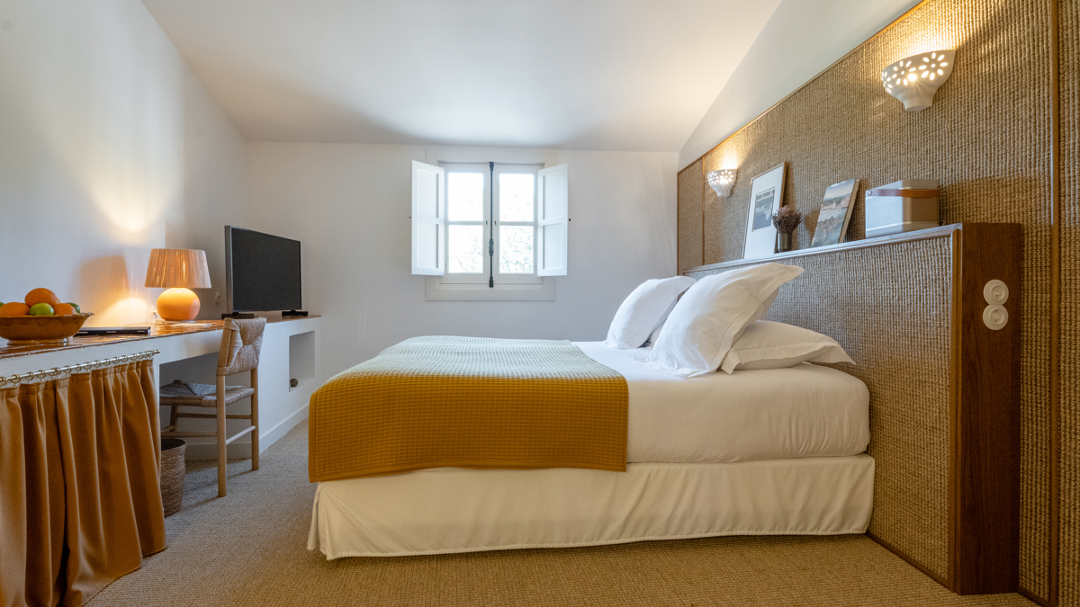 Une chambre bien organisée dispose d'un lit confortable avec une télévision placée juste en face.