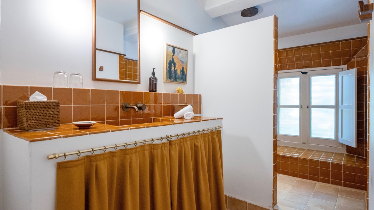 Une photo prise de la salle de bain montre un long miroir monté au-dessus du lavabo.