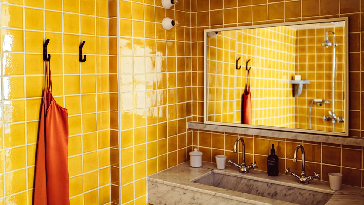 An orange-tiled bathroom is shown with each essential item properly placed and organized.