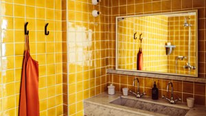 An orange-tiled bathroom is shown with each essential item properly placed and organized.