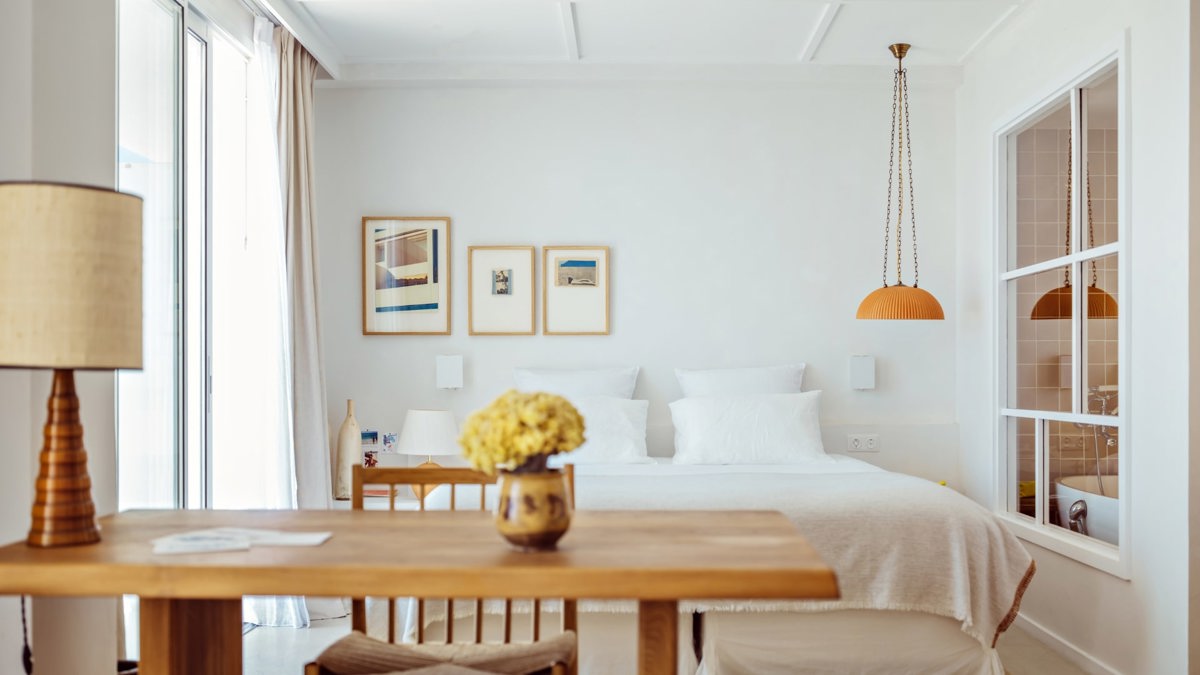 A well-organized bedroom features a cozy bed, a side table holding a lamp, and portraits mounted above.