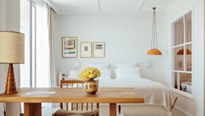 A well-organized bedroom features a cozy bed, a side table holding a lamp, and portraits mounted above.