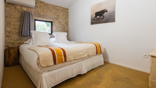 A tidy bedroom features a comfortable bed with a portrait mounted on the right wall.