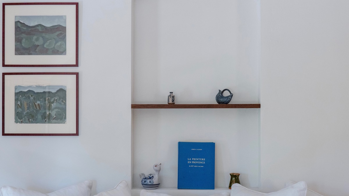 Objets décoratifs et carnet sur étagères murales, accompagnés de deux portraits adjacents.