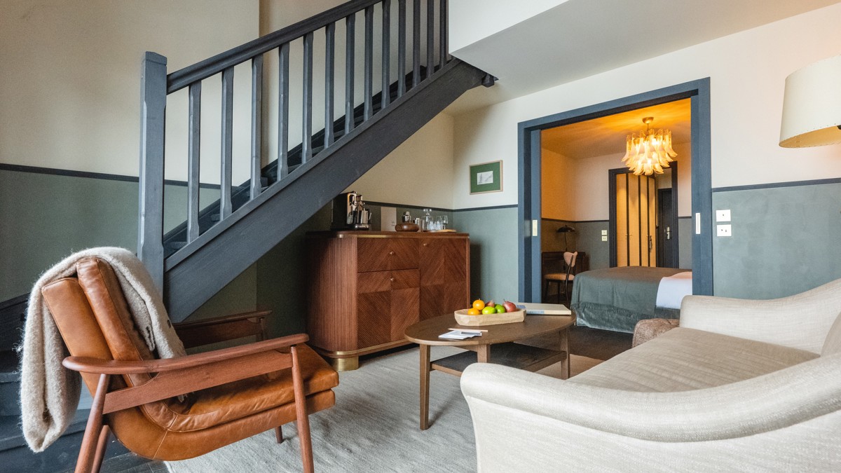 Un espace de vie comprend un canapé confortable situé près des escaliers et un placard en dessous.