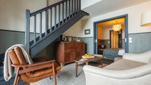 Un espace de vie comprend un canapé confortable situé près des escaliers et un placard en dessous.