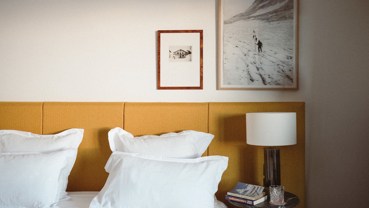 Two portraits are mounted above the bed’s side table, which holds a lamp.