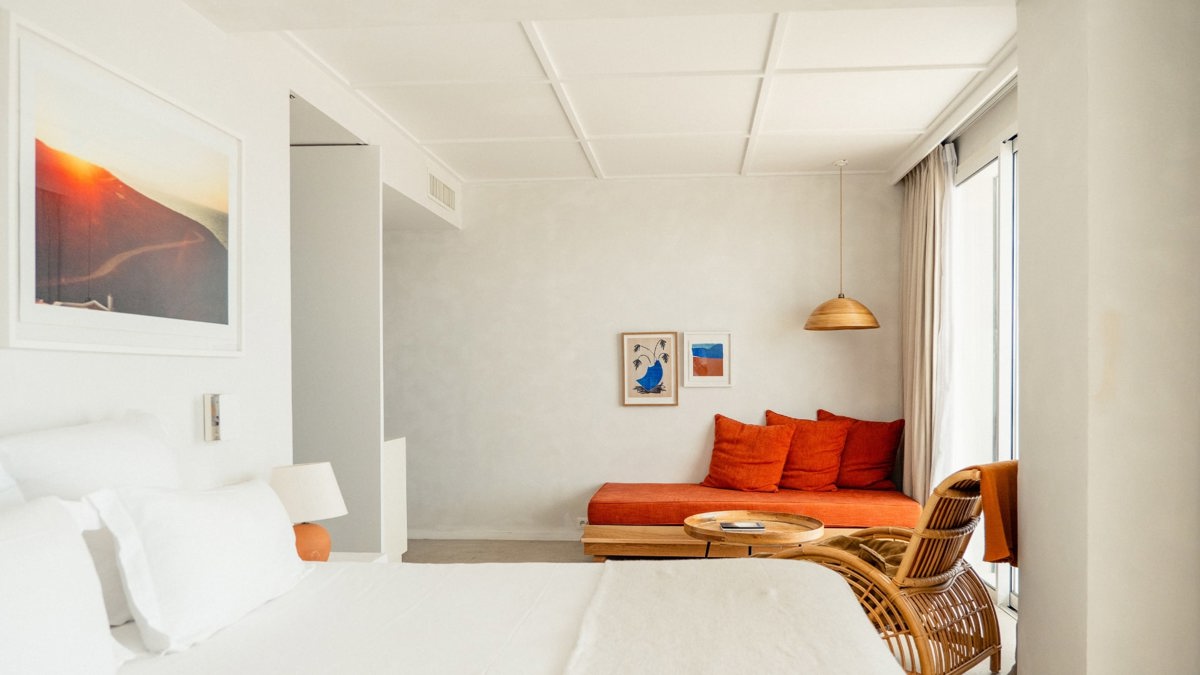 A well-organized bedroom showcases a cozy bed, a sofa chair in the corner, and portraits mounted above.