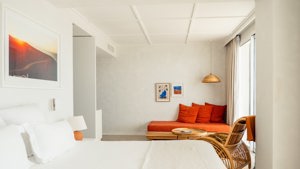 A well-organized bedroom showcases a cozy bed, a sofa chair in the corner, and portraits mounted above.