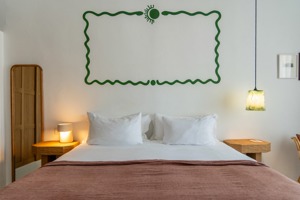 Une œuvre d’art est placée au-dessus de la tête de lit, avec un long miroir à proximité.
