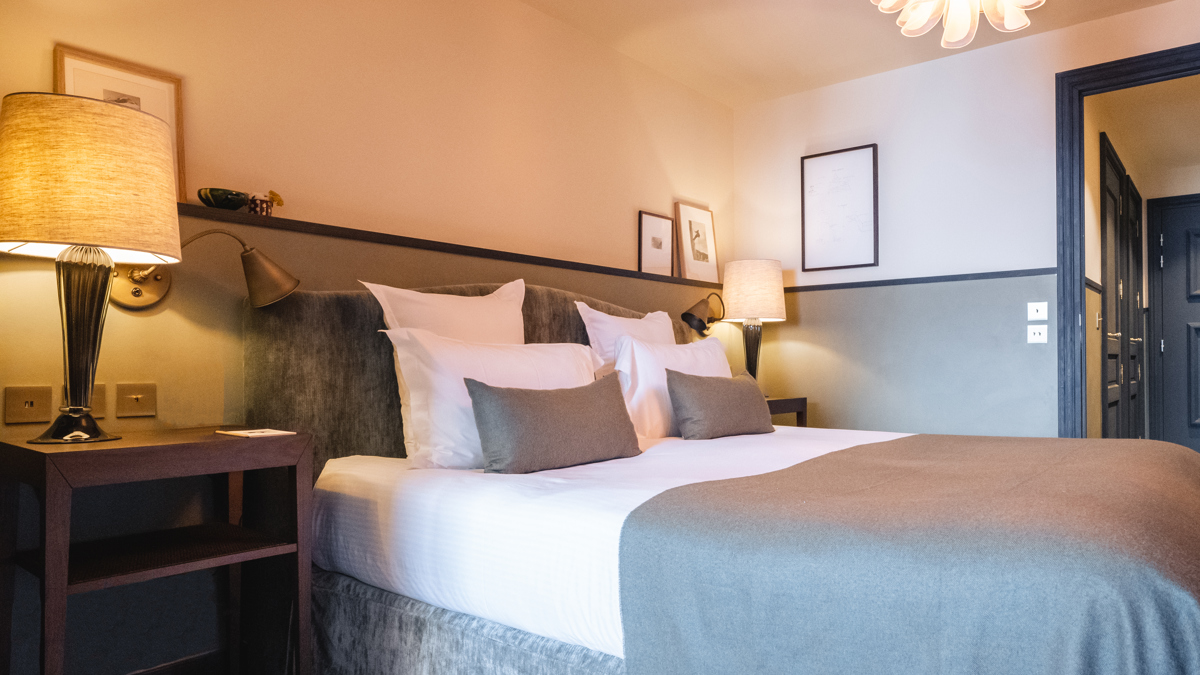 Une chambre comprend un lit confortable, deux tables de chevet avec des lampes et des portraits au-dessus.