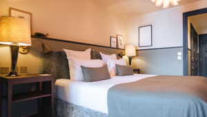 Une chambre comprend un lit confortable, deux tables de chevet avec des lampes et des portraits au-dessus.