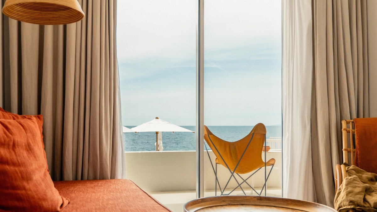 A relaxing chair is placed near the window, offering a beautiful view of lush greenery.