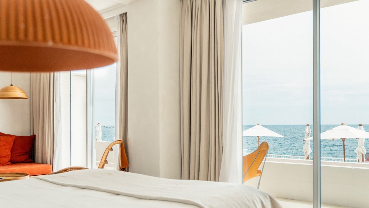 A bedroom’s balcony glass door offers a wonderful and breathtaking view of the ocean.