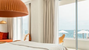 A bedroom’s balcony glass door offers a wonderful and breathtaking view of the ocean.