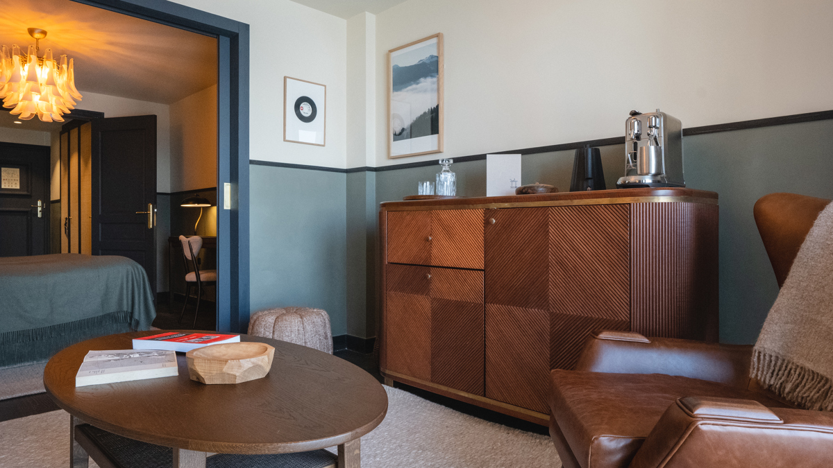 Une photo de l'espace de vie montre un canapé confortable et des portraits à côté de la chambre.