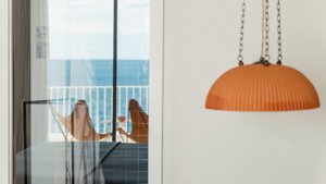 The reflection of the ocean is visible in the glass of the balcony door.