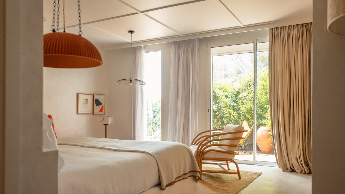 A cozy chair is placed near the bed, with the balcony glass door offering a wonderful greenery view.