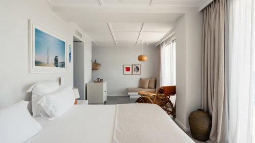A well-organized bedroom features a cozy bed, a nearby chair, and a portrait mounted above.