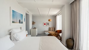 A well-organized bedroom features a cozy bed, a nearby chair, and a portrait mounted above.