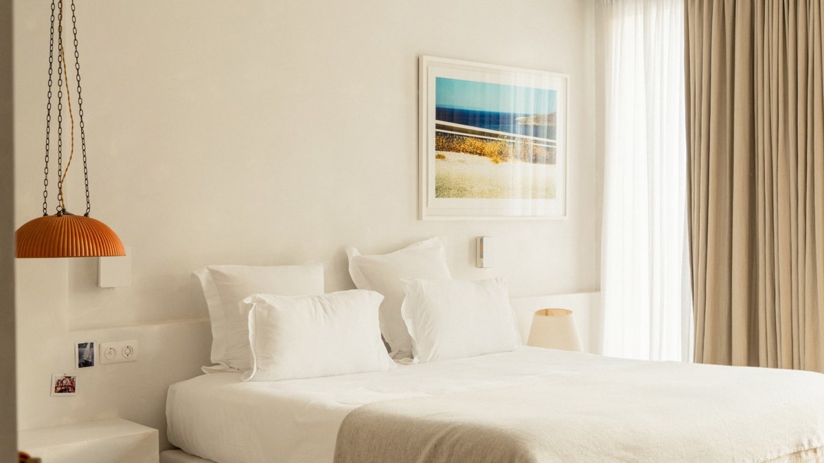 A properly arranged bedroom features a cozy bed, a hanging lamp, and portraits above.