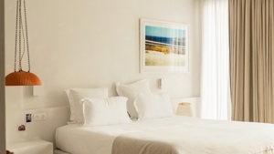 A properly arranged bedroom features a cozy bed, a hanging lamp, and portraits above.