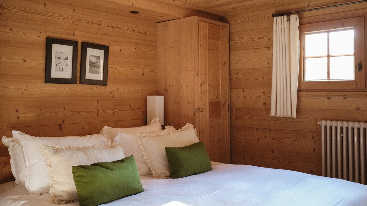 A well-organized bedroom features a cozy bed, soft pillows, and two portraits above.