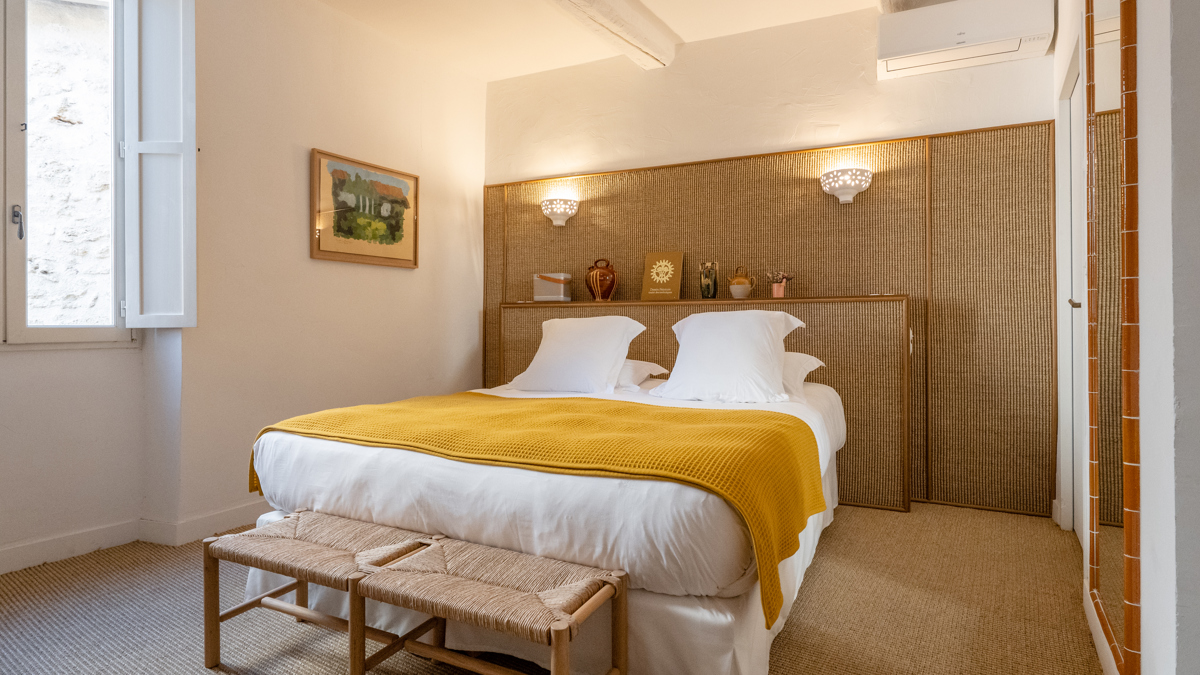 Une chambre bien organisée comprend un lit confortable avec un portrait accroché au mur de gauche.