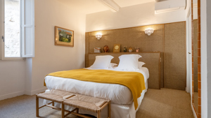 Une chambre bien organisée comprend un lit confortable avec un portrait accroché au mur de gauche.