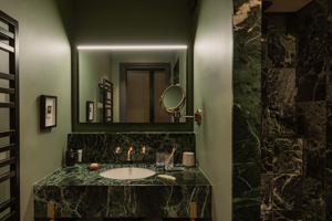 Salle de bains du Fitz Roy à Val Thorens, vasque en marbre vert, robinetterie laiton et miroir rétroéclairé