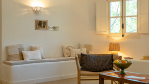 Une chaise confortable est placée près d'une table sur laquelle se trouve une corbeille de fruits.