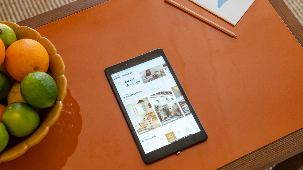 Une photo aérienne prise montre un iPad sur la table à côté d'une corbeille de fruits.