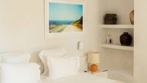 A side table holds a small lamp, with a portrait mounted just above the table.