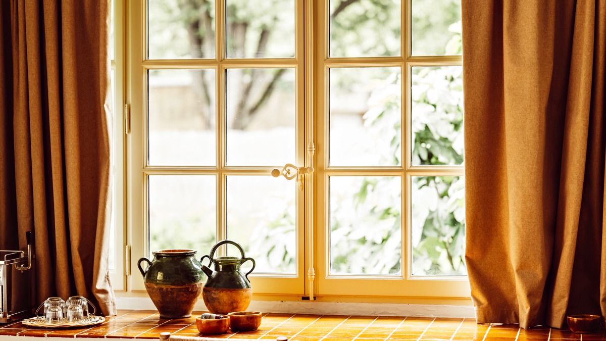 Un vase au design unique est placé près de la fenêtre en verre, offrant une belle vue sur la pelouse.
