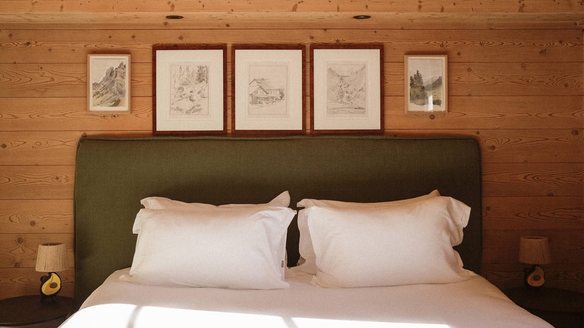 A well-organized bedroom showcases a cozy bed, two side tables with lamps, and portraits above.